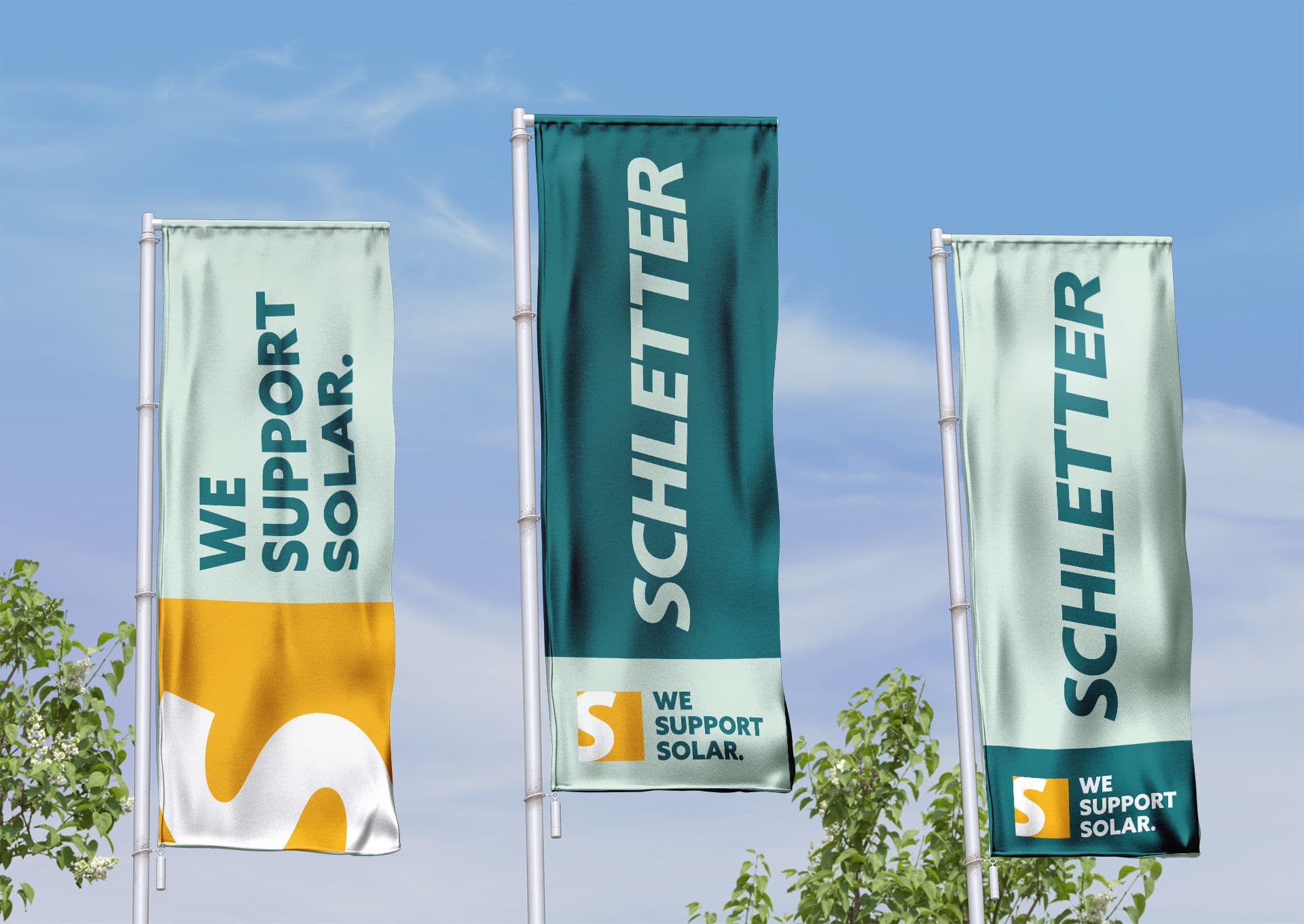 Three vertical flags display the text "SCHLETTER" and "WE SUPPORT SOLAR" against a blue sky backdrop, surrounded by some tree branches at the bottom.