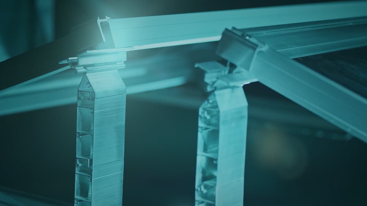 Close-up of metal framework structures, possibly parts of a building or machinery, illuminated with blue-green lighting.
