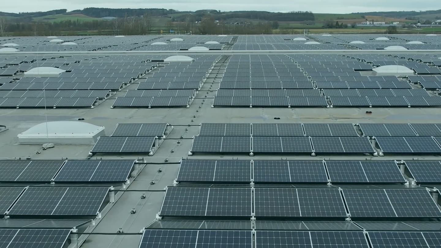 A large array of solar panels is installed on a rooftop in a rural area, capturing sunlight for energy production.